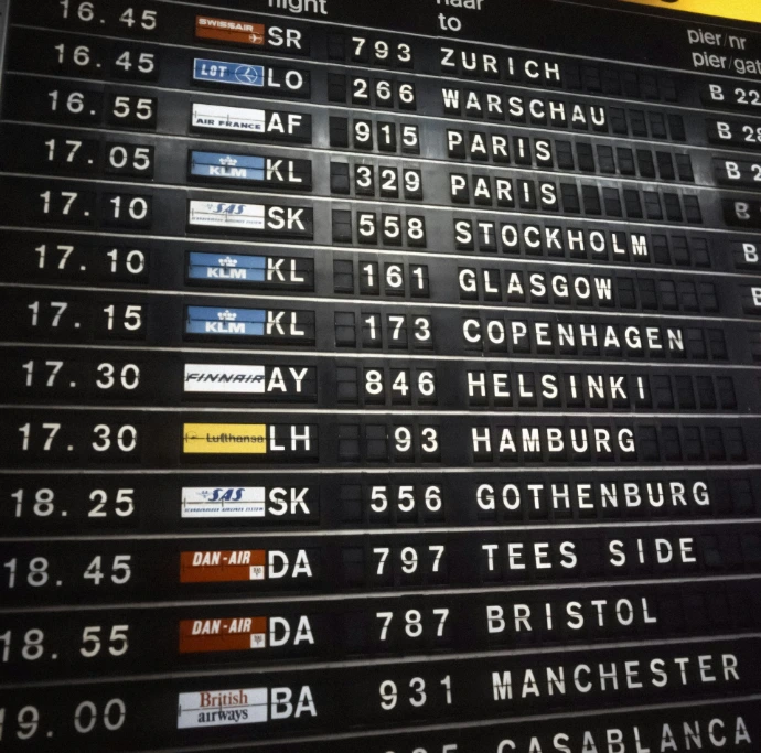 Airport departure board showing flight destinations and times.